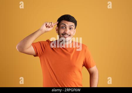 Aufgeregter brasilianischer Mann lächelnd, mit einem Finger auf den Kopf zeigend, tolle Idee oder Gedanke, gute Erinnerung Stockfoto