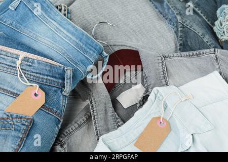 Stapel blauer Jeans, Hemden und leerer Etiketten aus Bastelpapier Stockfoto