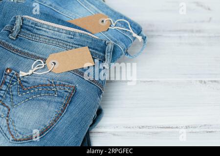 Ein Stapel blauer Jeans und leerer Anhänger auf weißem Hintergrund Stockfoto