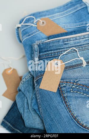 Ein Stapel blauer Jeans und leerer Anhänger auf weißem Hintergrund Stockfoto