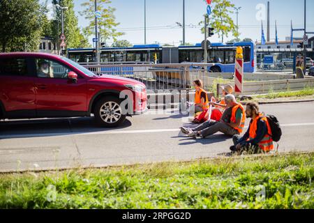 München, Deutschland. September 2023. Am 4. September 2023 blockierten Aktivisten der letzten Generation mehrere Straßen in München. Die LastGen sieht die bayerischen Politiker als schlimmste Klimapolitik-Blockierer. Ferner fordert die letzte Generation eine Geschwindigkeitsbegrenzung von 100 km/h auf Autobahnen, die Einführung eines neun-Euro-Tickets und einen Rat der Klimagesellschaft. (Foto: Alexander Pohl/SIPA USA) Credit: SIPA USA/Alamy Live News Stockfoto