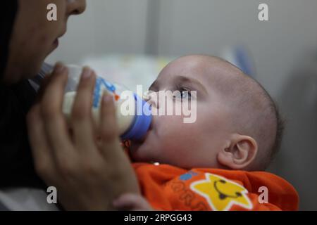 191015 -- HEBRON, 15. Oktober 2019 Xinhua -- Ein Freiwilliger ernährt Mohammed Muheisen, ein palästinensisches Baby aus dem Gazastreifen, das an einer Lungenerkrankung und einem gebrochenen Bein leidet, im Roten Halbmond-Krankenhaus in der Westbank-Stadt Hebron, 15. Oktober 2019. Das neun Monate alte Baby, das im September aus Gaza durch Israel zur Behandlung gebracht wurde, wurde von Freiwilligen betreut, nachdem seiner Mutter angeblich eine Reiserlaubnis verweigert wurde. Foto von Mamoun Wazwaz/Xinhua MIDEAST-HEBRON-BABY-HEALTH PUBLICATIONxNOTxINxCHN Stockfoto
