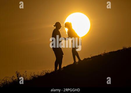 London, Großbritannien. 4. September 2023. Wetter in Großbritannien – die Menschen genießen den Sonnenuntergang auf den künstlichen Hügeln der Northala Fields in Northolt im Westen Londons. Das Met Office prognostiziert für die Woche hohe Temperaturen, die 30 °C berühren, da die Auswirkungen einer sogenannten iberischen Wolke in weiten Teilen des Landes spürbar sein werden. Quelle: Stephen Chung / Alamy Live News Stockfoto