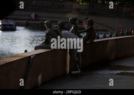 Berlin, Deutschland. September 2023. Drei Männer machen eine Pause in der Gruppe der Figuren "drei Mädchen und ein Junge", gegenüber der Kathedrale. Die Figuren des Künstlers Wilfried Fitzenreiter sind ein beliebtes Fotomotiv. Quelle: Paul Zinken/dpa/Alamy Live News Stockfoto