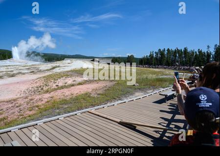 Besucher beobachten den Geysir Old Faithful im Yellowstone-Nationalpark Stockfoto