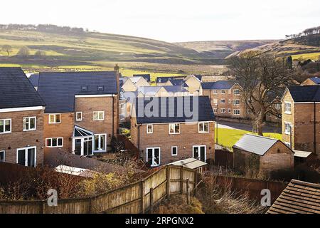 Ein Wohnhaus in Derbyshire an einem späten Nachmittag im März, als eine niedrige Sonne lange Schatten über einen Hügel und die zwei- und dreistöckigen Anwesen streute Stockfoto