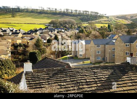 Ein Wohnhaus in Derbyshire an einem späten Nachmittag im März, als eine niedrige Sonne lange Schatten über einen Hügel und die zwei- und dreistöckigen Anwesen streute Stockfoto