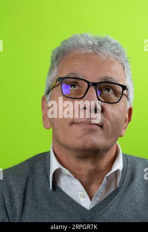 Porträt eines lächelnden grauhaarigen Seniors, der nach oben schaut. Reifer kaukasischer Mann, der eine Brille auf farbigem Hintergrund trägt Stockfoto