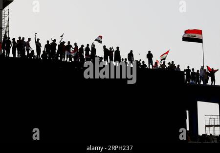 191027 -- PEKING, 27. Oktober 2019 -- Demonstranten schwenken während eines Protestes auf dem Tahrir-Platz in Bagdad, Irak, am 26. Oktober 2019 Flaggen auf dem Dach eines Gebäudes. XINHUA FOTOS DES TAGES KhalilxDawood PUBLICATIONxNOTxINxCHN Stockfoto
