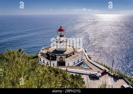 Blick auf den historischen Leuchtturm Farol Ponta do Arnel, der sich an den Klippen in Nordeste, Sao Miguel Island, Azoren, Portugal anschmiegt. Der noch aktive Leuchtturm war der erste, der 1876 auf den Azoren gebaut wurde. Stockfoto