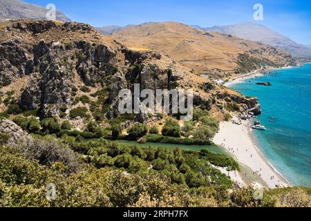 Entdecken Sie ein irdisches Paradies, während Sie den Preveli Beach neben einem üppigen Palmenwald bestaunen. Ein kristallklarer Strom verschmilzt sanft mit dem azurblauen Wasser Stockfoto