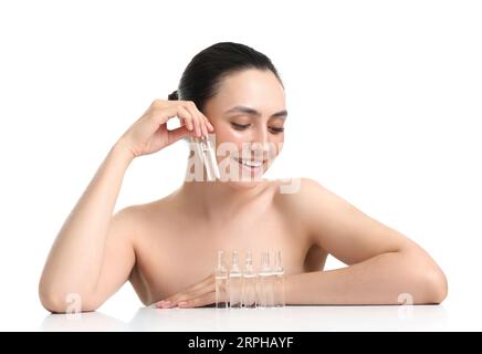 Schöne junge Frau mit Ampullen auf dem Tisch vor weißem Hintergrund Stockfoto