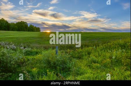 Die letzten Sonnenstrahlen, die ein Heufeld im Norden Wisconsins beleuchten. Stockfoto