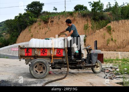 191122 -- YICHENG COUNTY, 22. November 2019 -- Ein Dorfbeamter pumpt Wasser aus, das in einer Schlammgrube gespeichert ist, bevor er das Wasser an die Dorfbewohner im Nanling Village im Yicheng County, Provinz Shanxi in Nordchina, am 3. Juli 2019 verteilt. Als der Schalter gezogen wurde, sprang Wasser aus 403 Metern Tiefe heraus. Nanling Village's allererster Tiefwasserbrunnen wurde an einem frühen Wintermorgen in Betrieb genommen. In der Vergangenheit hatte sich das Dorf, das sich über die Schluchten des Zhongtiao-Gebirges im Norden Chinas ausbreitete, jahrhundertelang ausschließlich auf Schlammgruben verlassen, um sein wertvolles Trinkwasser zu speichern. Von der Angst vor der Dürre heimgesucht Stockfoto