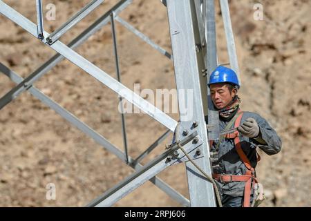 191128 -- TAXKORGAN, 28. November 2019 -- Ein Techniker arbeitet an einem elektrischen Übertragungsturm in der autonomen Provinz Taxkorgan im Nordwesten Chinas, Xinjiang Uygur Autonomous Region, 23. November 2019. Die Township Maryang und die Township Datong liegen auf dem Pamir Plateau inmitten hoher Berge und tiefer Täler, weit entfernt vom County Seat. Lange Zeit führt das Gelände zu einer langsamen Entwicklung der Macht und anderer Infrastrukturen, die zum Haupthindernis für die lokale Armutsbekämpfung geworden sind. Selbst die von der Regierung eingerichteten Photovoltaik-Stromversorgungsmodule können nur die grundlegenden Beleuchtungsbedürfnisse erfüllen Stockfoto