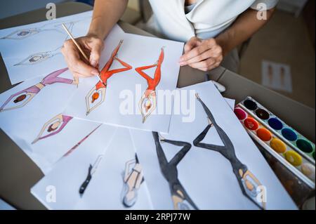 Eine gesichtslose Frau zeichnet Aquarelle von Sportbekleidung. Nahaufnahme der Hände eines Modedesigners. Stockfoto