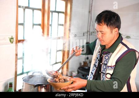 191201 -- SHILIN, 1. Dezember 2019 -- BI Xingxue bereitet Essen für die Touristen in einem von ihm und seiner Frau Li Xuezhi betriebenen Agritainment-Restaurant im Dorf Danuohei der Gemeinde Guishan im autonomen Kreis Shilin Yi, Provinz Yunnan im Südwesten Chinas, 28. November 2019. Danuohei Village, mit einer Geschichte von über 600 Jahren, ist ein gut geschütztes altes Dorf der Yi-ethnischen Kultur. Die Anwohner bauten Häuser und Straßen mit Steinen, was es als ein Steindorf einzigartig macht. Es ist umgeben von Bergen, Flüssen und einer wunderschönen Landschaft. Das Dorf hat heute 370 Haushalte mit einer Bevölkerung von 1.000, von wh Stockfoto