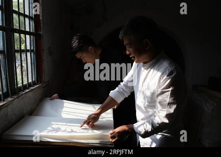 191209 -- JINGXIAN, 9. Dezember 2019 -- Cao Jianqin R und sein Sohn Cao Li überprüfen die Qualität des Xuan-Papiers in der Zijinlou Xuan-Papierfabrik im Jingxian County, Stadt Xuancheng in der ostchinesischen Provinz Anhui, 8. November 2019. Xuan-Papier, traditionelles chinesisches Papier, das im Jingxian County in der Stadt Xuancheng hergestellt wird, hat eine Geschichte von mehr als 1.000 Jahren. Bei mehr als 100 Verfahren kostet die Herstellung des Papiers mindestens ein Jahr, um das Material in das Endprodukt zu verwandeln. Das Papier ist bekannt für seine ausgezeichnete Handwerkskunst, seine feine Qualität und seine lange Haltbarkeit. Es wird von chinesischen Künstlern und Kalligrafen geschätzt Stockfoto