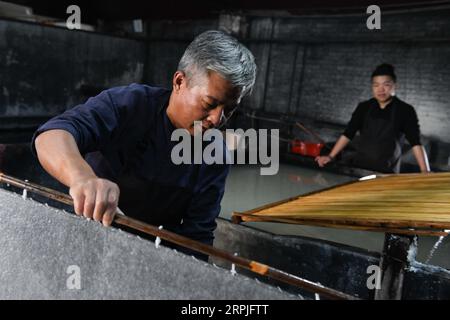 191209 -- JINGXIAN, 9. Dezember 2019 -- Cao Jianqin und sein Sohn Cao Li machen Xuan-Papier in der Zijinlou Xuan-Papierfabrik im Jingxian County, Stadt Xuancheng in der ostchinesischen Provinz Anhui, 8. November 2019. Xuan-Papier, traditionelles chinesisches Papier, das im Jingxian County in der Stadt Xuancheng hergestellt wird, hat eine Geschichte von mehr als 1.000 Jahren. Bei mehr als 100 Verfahren kostet die Herstellung des Papiers mindestens ein Jahr, um das Material in das Endprodukt zu verwandeln. Das Papier ist bekannt für seine ausgezeichnete Handwerkskunst, seine feine Qualität und seine lange Erhaltungszeit und wird von chinesischen Künstlern und Kalligraphen geliebt und wird PA genannt Stockfoto