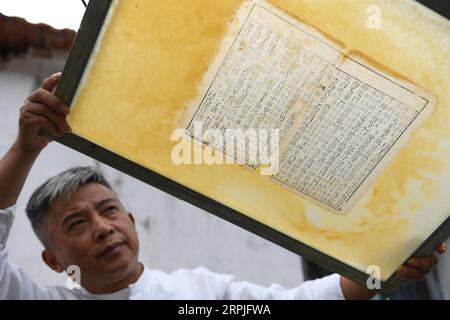 191209 -- JINGXIAN, 9. Dezember 2019 -- Cao Jianqin zeigt reparierte Seiten eines antiken Buches in der Zijinlou Xuan Papierfabrik im Jingxian County, Xuancheng Stadt in der ostchinesischen Provinz Anhui, 22. Oktober 2019. Xuan-Papier, traditionelles chinesisches Papier, das im Jingxian County in der Stadt Xuancheng hergestellt wird, hat eine Geschichte von mehr als 1.000 Jahren. Bei mehr als 100 Verfahren kostet die Herstellung des Papiers mindestens ein Jahr, um das Material in das Endprodukt zu verwandeln. Das Papier ist bekannt für seine ausgezeichnete Handwerkskunst, seine feine Qualität und seine lange Erhaltungszeit und wird von chinesischen Künstlern und Kalligraphen geliebt und wird PA genannt Stockfoto