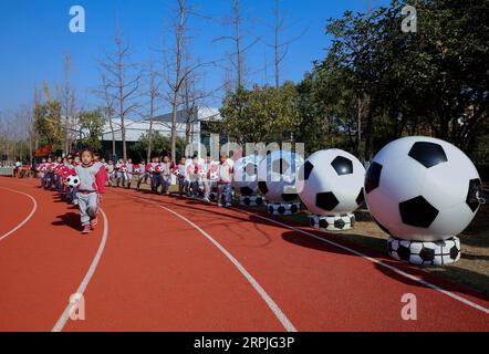 191209 -- CHANGXING, 9. Dezember 2019 -- Schüler betreten den Spielplatz während der Eröffnungszeremonie einer Fußballaktivität in einem Kindergarten im Bezirk Changxing der ostchinesischen Provinz Zhejiang, 9. Dezember 2019. CHINA-ZHEJIANG-CHANGXING-FUN GAMES-FOOTBALL CN XUXYU PUBLICATIONXNOTXINXCHN Stockfoto