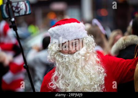 191214 -- NEW YORK, 14. Dezember 2019 -- Ein als Weihnachtsmann verkleideter Mann posiert für ein Selfie während der SantaCon 2019 in New York, USA, 14. Dezember 2019. In Weihnachtsmannkostümen oder festlichen Kostümen versammelten sich am Samstag Hunderte von Menschen auf dem Times Square zur SantaCon 2019, um die weihnachtliche Atmosphäre zu genießen und Geld für wohltätige Zwecke zu sammeln. U.S.-NEW YORK-2019 SANTA CON WangxYing PUBLICATIONxNOTxINxCHN Stockfoto