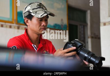 191221 -- HAIKOU, 21. Dezember 2019 -- LYU Shiyang, ein Waldranger im Qinglangang Provincial Nature Reserve, überprüft die Fotos, die er in seinem Büro im Reservat in der südchinesischen Provinz Hainan am 17. Dezember 2019 gemacht hat. Hainan, reich an Mangrovenvorkommen, verfügt heute über etwa 5.727 Hektar Mangrovenwälder, von denen die meisten in einer Vielzahl von Schutzgebieten - Naturschutzgebieten und Feuchtgebieten - verteilt sind. Chen Zhengping, Feng Erhui, Luo Lixiang und LYU Shiyang sind Mangroven, die das Personal in verschiedenen Mangrovenreserven in der Provinz Hainan schützen und managen Stockfoto