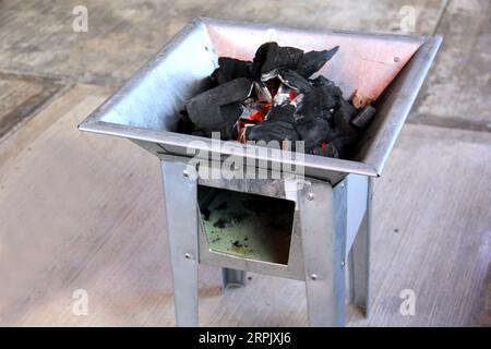 Holzkohlestücke auf einem Grillherd, die ein Feuer zum Kochen oder Braten von Fleisch anzünden Stockfoto