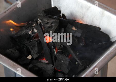 Holzkohlestücke auf einem Grillherd, die ein Feuer zum Kochen oder Braten von Fleisch anzünden Stockfoto