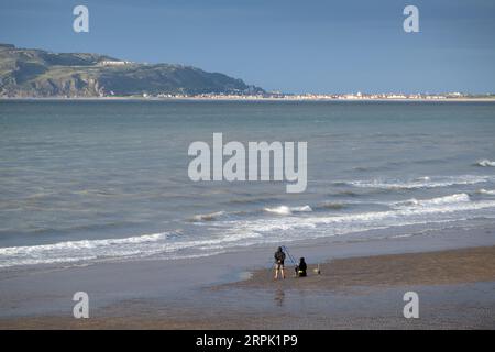 Leute fischen am Strand in Nordwales, mit Landudno und dem Great Orme in der Backgroup. Wales, Großbritannien. Stockfoto