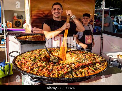 Ein Koch bereitet eine sehr große Paella auf den Mindil Beach Sunset Markets in Darwin, Northern Territory, zu und serviert sie Stockfoto