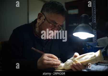 191226 -- PEKING, 26. Dezember 2019 -- Li Chunke macht eine Schnitzerei auf Mammutzahn in einer Werkstatt des Pekinger Polytechnikum für Leichtindustrie in Peking, Hauptstadt von China, 25. Dezember 2019. Zahnschnitzerei, ursprünglich Schnitzen auf Elfenbein, ist eine traditionelle Kunst im alten China. Es stellte den Höhepunkt der Volkskunst in China während der Qing-Dynastie 1644-1911 dar und wurde in der Dekoration für den königlichen Hof populär. China hat seine Bemühungen im Bereich des Schutzes der wildlebenden Tiere im Laufe der Jahre verstärkt. Am 31. Dezember 2016 erklärte China, es werde innerhalb eines Jahres eine vollständige Einstellung seines inländischen Elfenbeinhandels durchsetzen. Auf D Stockfoto