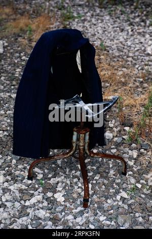 Anzug Jacke hängt auf einem kaputten und kaputten Drehstuhl auf einem Feld Stockfoto