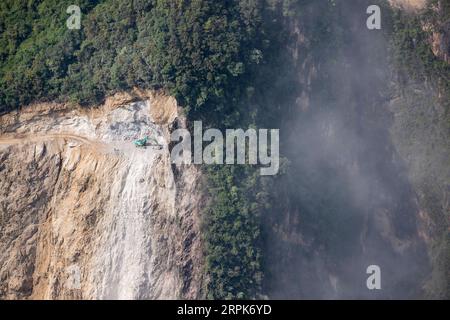 200101 -- PEKING, 1. Januar 2020 -- Ein Traktor arbeitet an Straßenbauarbeiten an einer Klippe im Dorf Abuluoha im Butuo County der Autonomen Präfektur Liangshan Yi, Provinz Sichuan im Südwesten Chinas, 18. Juli 2019. Am Dienstag wurde eine Seilbahn eingerichtet, um den Dorfbewohnern auf einer Klippe freie Fahrten zu ermöglichen. Die etwa 420 Meter lange und mehr als 400 Meter hohe Seilbahn verbindet das Dorf Abuluoha auf bequemere Weise mit der Außenwelt. Umgeben von Bergen, hat das Dorf mit über 250 Einwohnern in Isolation und Armut seit mehr als 50 Jahren gesessen. In der Vergangenheit mussten die Menschen mindestens drei ausgeben Stockfoto