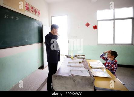 200105 -- PEKING, 5. Januar 2020 -- Wang Beihai L lehrt Chen Weiyu, wie man einen Anruf an der Sanhe Grundschule in der Dabaidi Gemeinde Ruijin, ostchinesische Provinz Jiangxi, macht, 8. Mai 2019. Die Sanhe Elementary School, die sich tief in den Bergen von Ruijin befindet, hat nur einen Lehrer, den 46-jährigen Wang Beihai, und einen Schüler Chen Weiyu, einen 9-jährigen Jungen aus einer armseligen Familie. XINHUA-BILDER DES JAHRES 2019 LanxHongguang PUBLICATIONxNOTxINxCHN Stockfoto