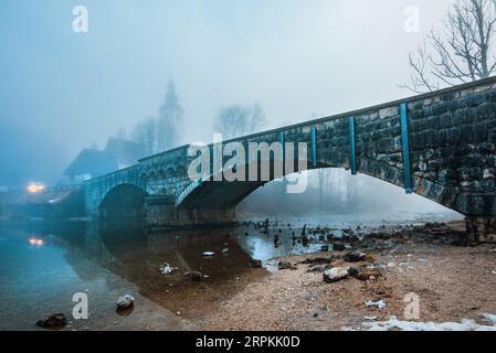 Alte Steinbrücke am Bohinjer See am nebeligen Morgen, ruhige Szene von Sloweniens Reiseziel in der Dämmerung, selektiver Fokus Stockfoto