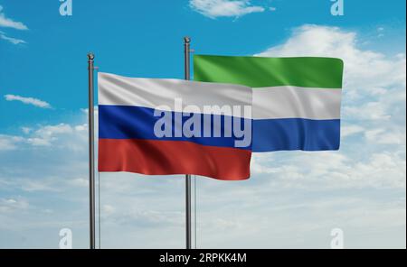 Sierra Leone oder die Flagge von Salone und Russland, die im Wind am blauen Himmel zusammenwinken, zwei Konzepte der Länderzusammenarbeit Stockfoto