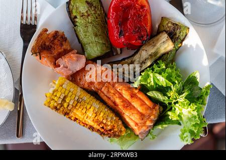 Frisch gekochtes gegrilltes Gemüse auf einem weißen Gericht. Gegrillter roter Fisch mit Gemüse. Ansicht von oben. Stockfoto