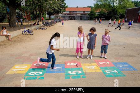 Niederlande, Arnhem, Kinder spielen auf dem Schulhof Hopscotch. Stockfoto