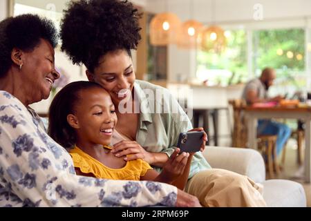 Multi-Generation Weibliche Familie Posiert Für Selfie Auf Handy Sitzend Auf Sofa Zu Hause Zusammen Stockfoto