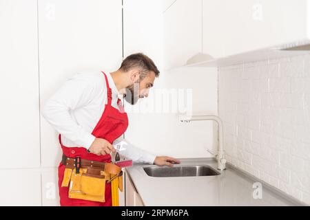 Klempner installiert Küchenarmatur. Sanierung in der Wohnung. Stockfoto