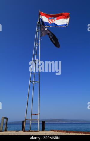 Kroatische Flagge und Piratenflagge auf einem hohen Mast Stockfoto