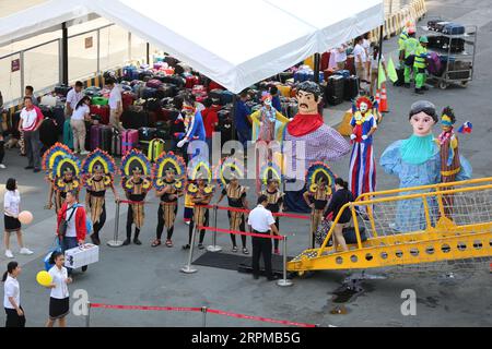 Philippinische fiesta-Motto Willkommensfeier für Kreuzfahrtschiff am Manila Pier : Musiker mit Bambusinstrumenten, philippinische Tänzer, Higantes, Flaggen Stockfoto