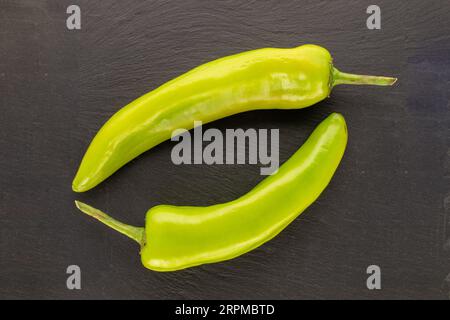 Zwei grüne Chilischoten auf Schieferstein, Makro, Draufsicht. Stockfoto