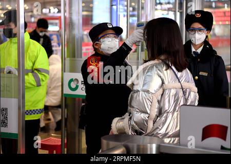 200211 -- XI AN, 11. Februar 2020 -- Ein Polizist des Nordbahnhofs Xi an misst die Temperatur der Passagiere am Ausgang des Nordbahnhofs Xi an in Xi an, Provinz Shaanxi im Nordwesten Chinas, 10. Februar 2020. Mit der Zunahme des Passagierflusses in verschiedenen Verkehrsknotenpunkten hat Xi an ein Netzmanagementsystem für Personen eingeführt, die nach Xi an kommen. Alle Personen, die Xi an über den Xianyang International Airport, Xi an Railway Station, Xi an North Railway Station, Xi an South Railway Station, Huyi Railway Station und Epang Palace Railway Station erreichen, müssen klassifiziert und einer von ihnen überprüft werden Stockfoto