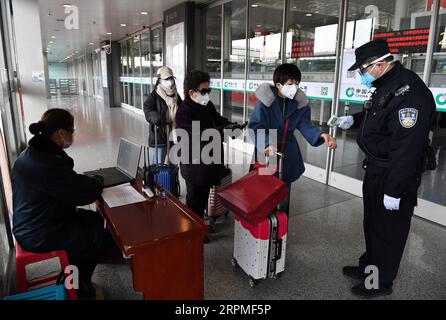 200211 -- XI AN, 11. Februar 2020 -- Ein Polizist des Nordbahnhofs Xi an misst die Temperatur der Passagiere an einem Eingang zum Nordbahnhof Xi an in Xi an, Provinz Shaanxi im Nordwesten Chinas, 10. Februar 2020. Mit der Zunahme des Passagierflusses in verschiedenen Verkehrsknotenpunkten hat Xi an ein Netzmanagementsystem für Personen eingeführt, die nach Xi an kommen. Alle Personen, die Xi an über den Xianyang International Airport, Xi an Railway Station, Xi an North Railway Station, Xi an South Railway Station, Huyi Railway Station und Epang Palace Railway Station erreichen, müssen klassifiziert und kontrolliert werden Stockfoto