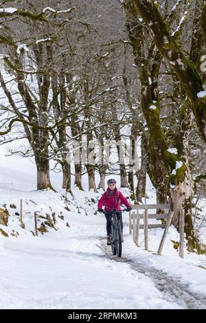 Nette Seniorin, die an einem sonnigen Wintertag in den Allgaeu-Alpen bei Oberstdorf, Bayern, mit dem E-Mountainbike unterwegs ist Stockfoto