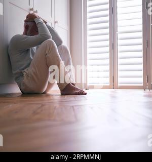 Depressiver Älterer Mann, Der Mit Schlechter Psychischer Gesundheit Leidet, Sitzt Zu Hause Auf Dem Boden Stockfoto