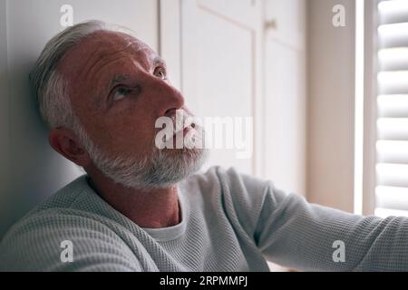 Nahaufnahme Des Depressiven Älteren Mannes, Der Mit Schlechter Psychischer Gesundheit Leidet, Der Zu Hause Auf Dem Boden Sitzt Stockfoto