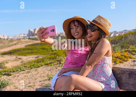 Freundinnen in Hut sehr glücklich auf Strandurlaub machen ein Selfie mit Telefon, Sommer Reise Freunde Freundschaftskonzept Stockfoto